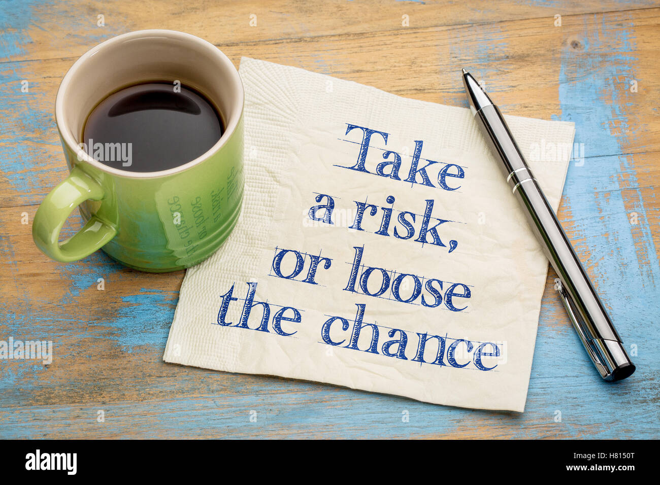 Take a risk or loose the chance - handwriting on a napkin with a cup of espresso coffee Stock Photo