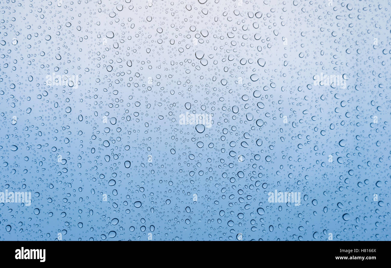 Background of close focus on graduated blue tone from soft to dark of drop of rain water on window glass after raining on rainy Stock Photo