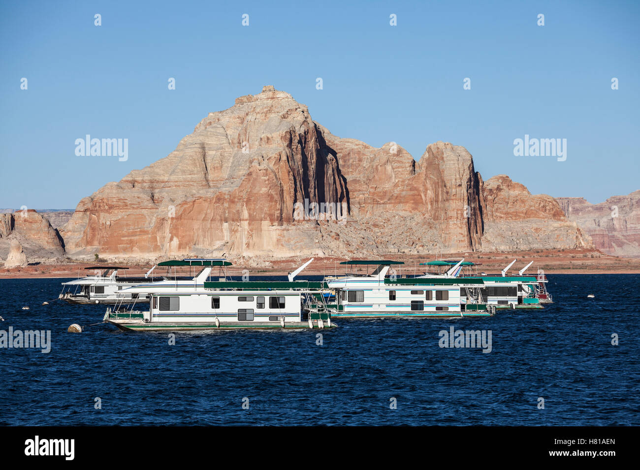 Desert sandstone peaks and houseboats on Lake Powell in the Glen Canyon National Recreation Area. Stock Photo