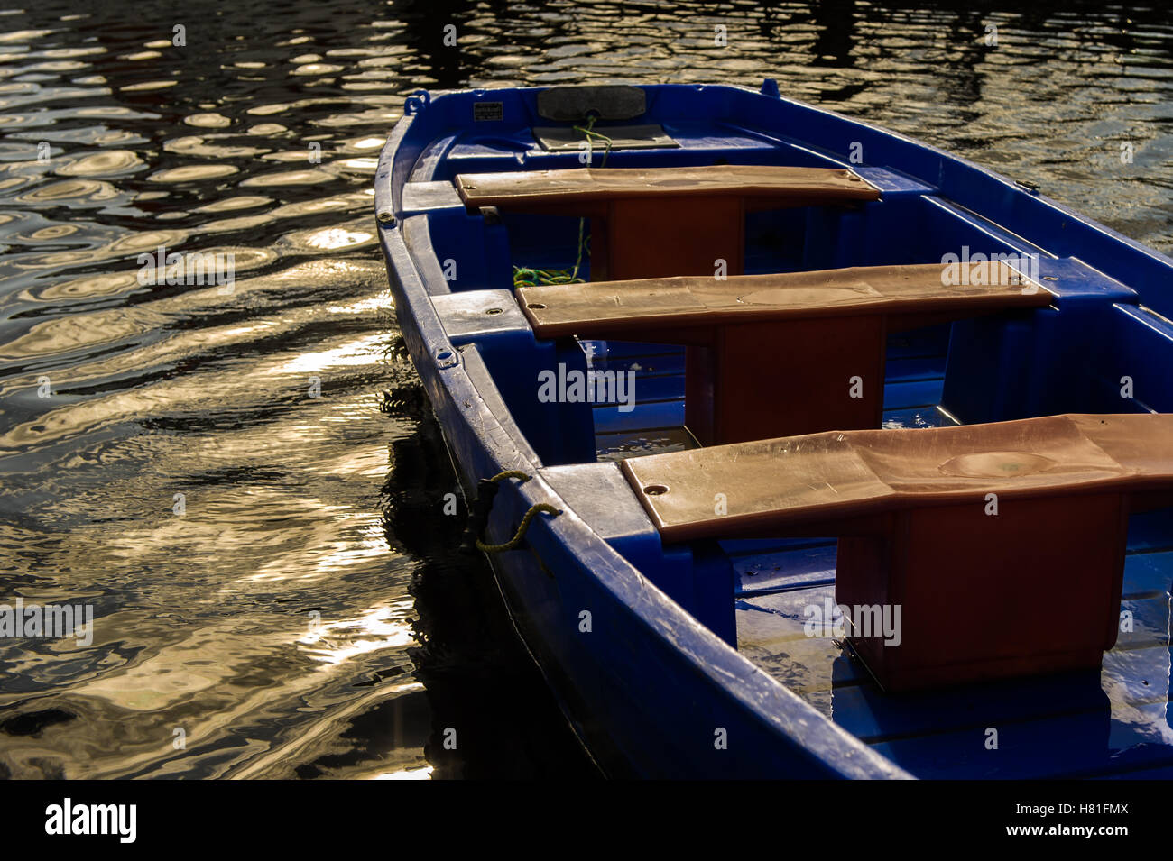 Small blue rowing boat moored on water. Stock Photo