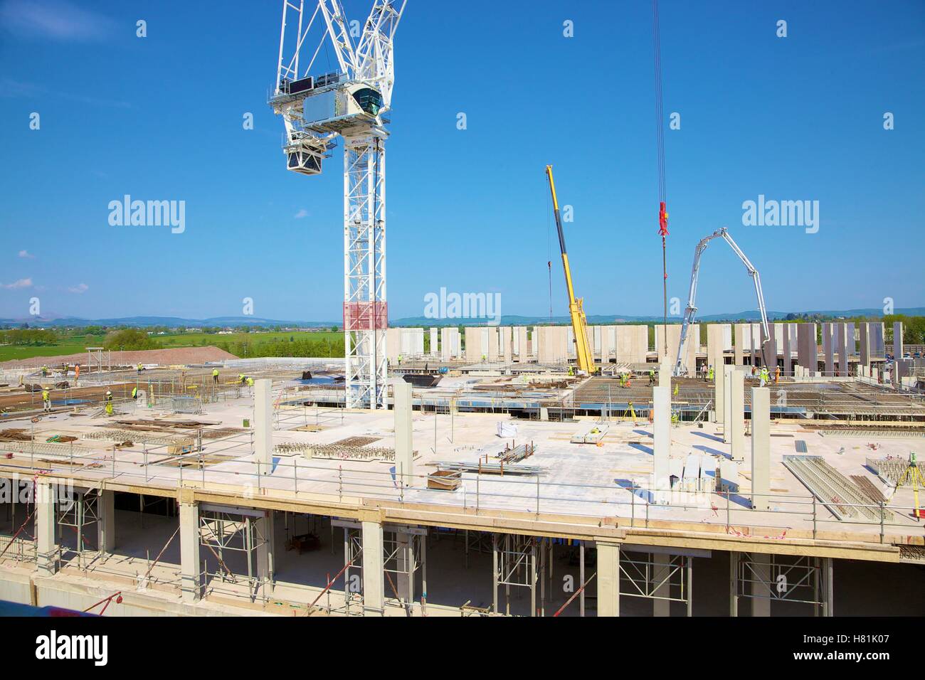Prefabricated construction using a crane. Workers wearing safety clothing on the building site. Stock Photo