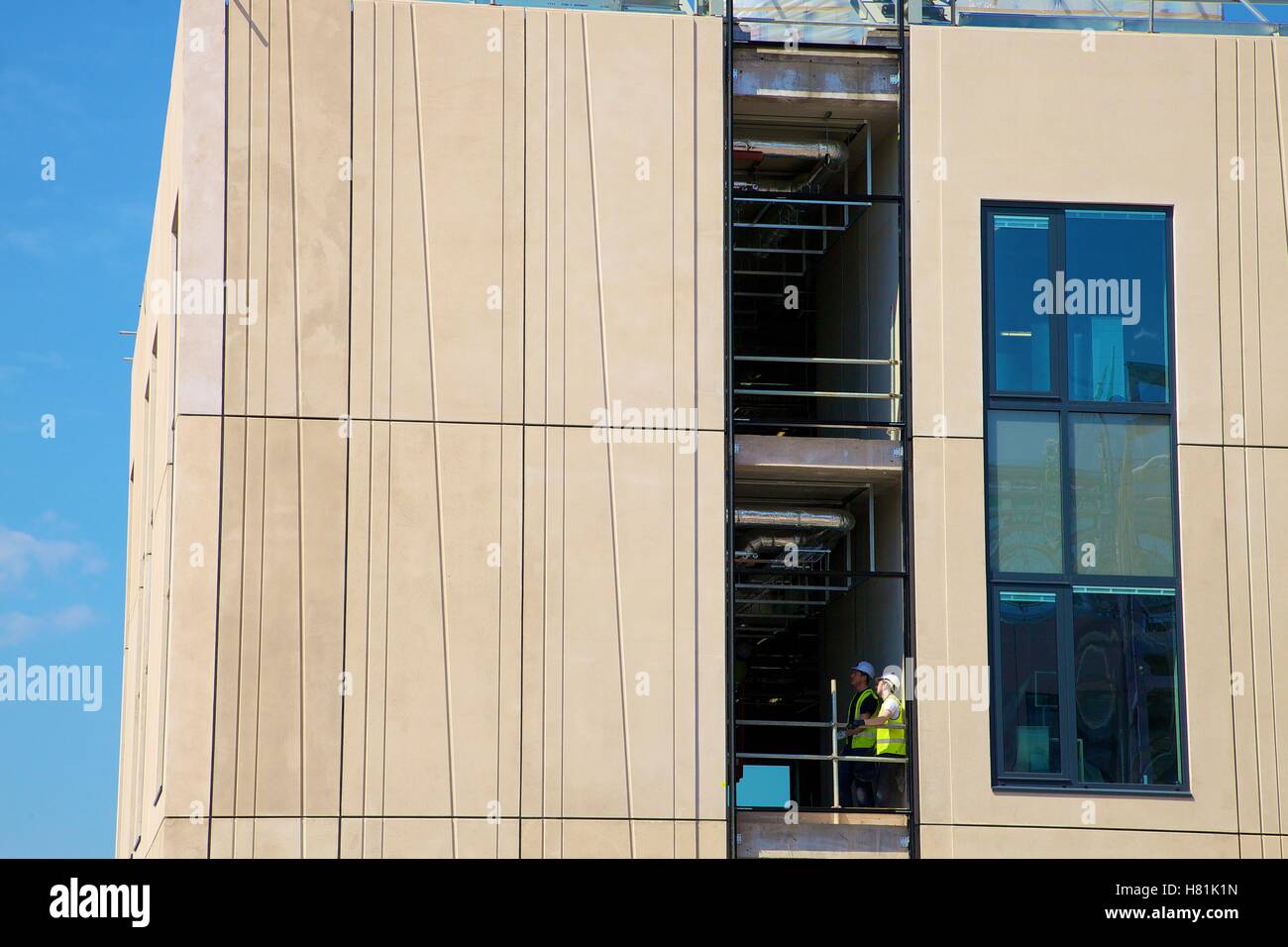 Curtain wall construction. Workers wearing safety clothing inspecting the build. Stock Photo