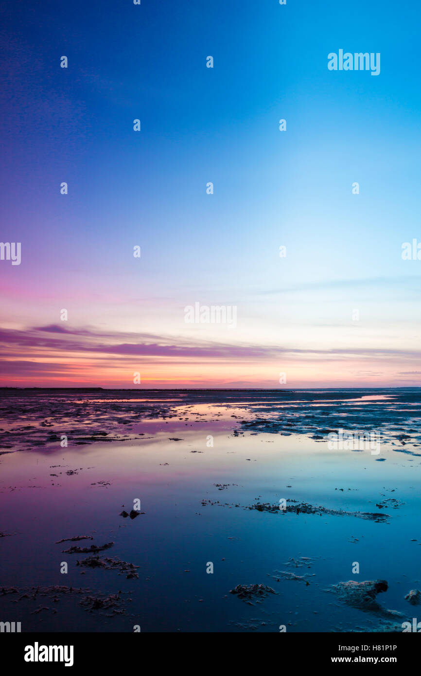 Colorful pink sunset over the North Sea with a calm blue ocean and ...