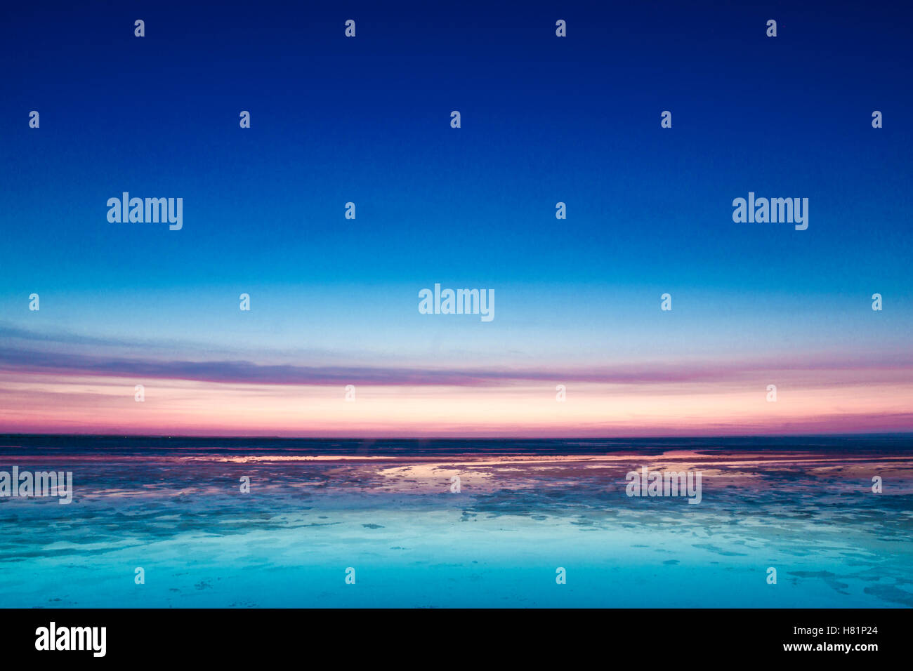 Colorful pink sunset over the North Sea with a calm blue ocean and ...