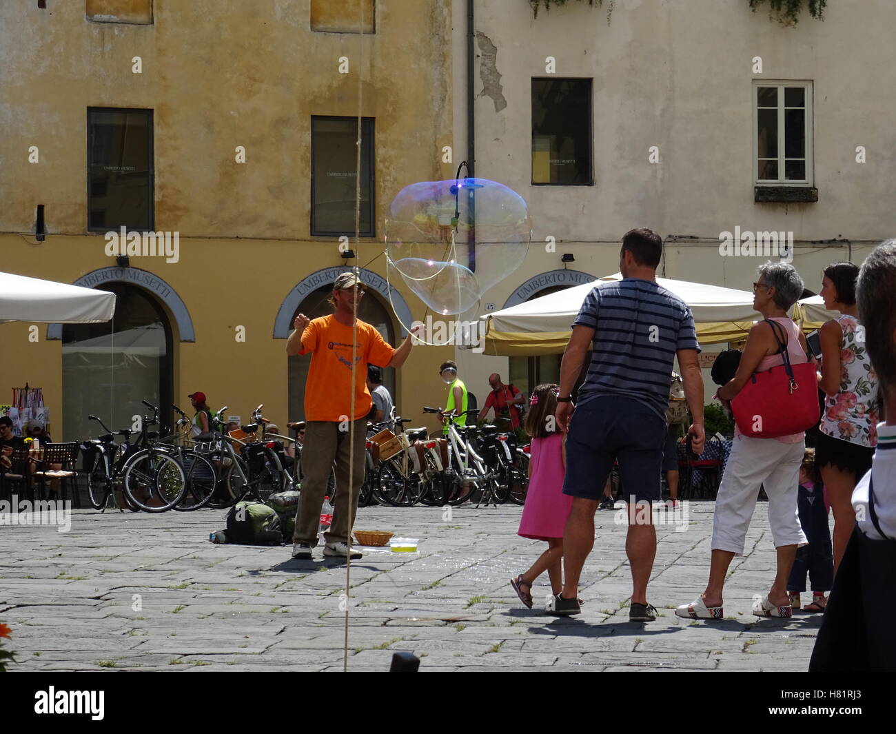 Street entertainer creating large bubbles to entertain a small crowd Stock Photo
