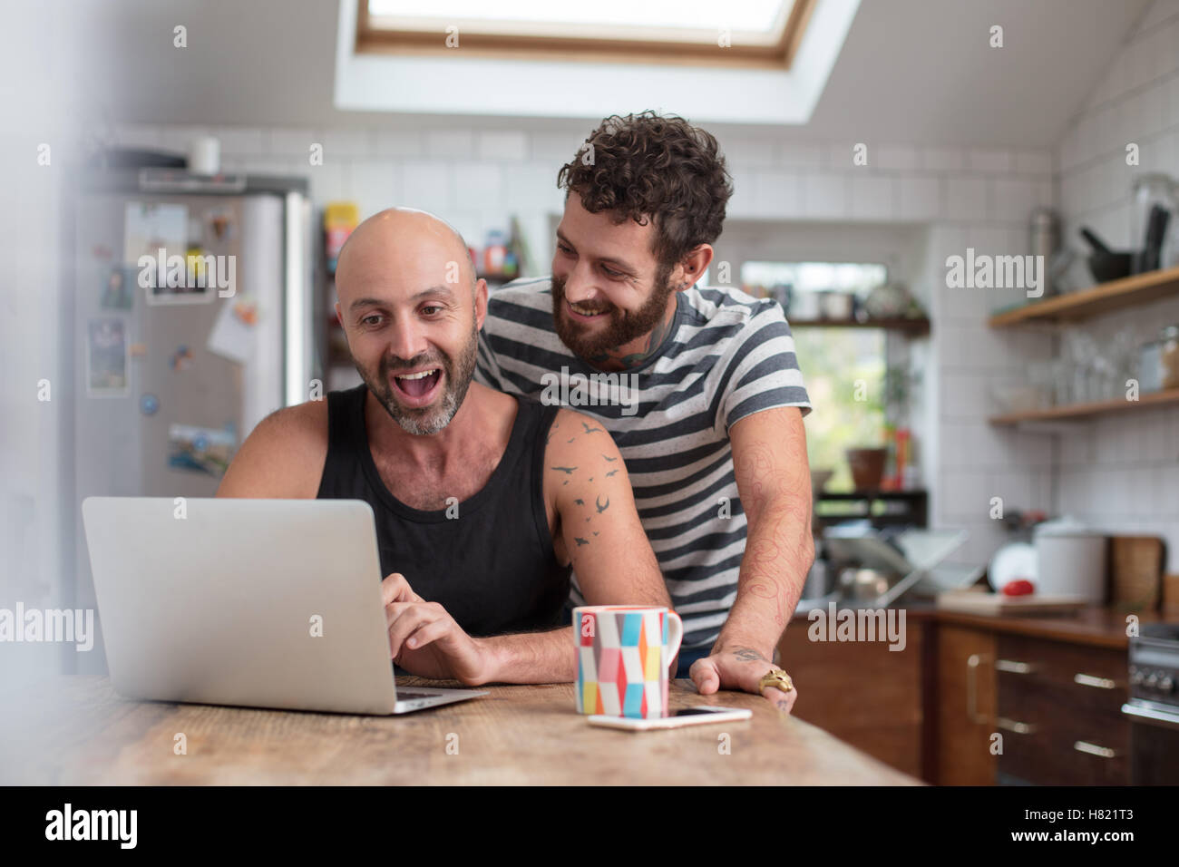 Gay couple using laptop in the kitchen Stock Photo