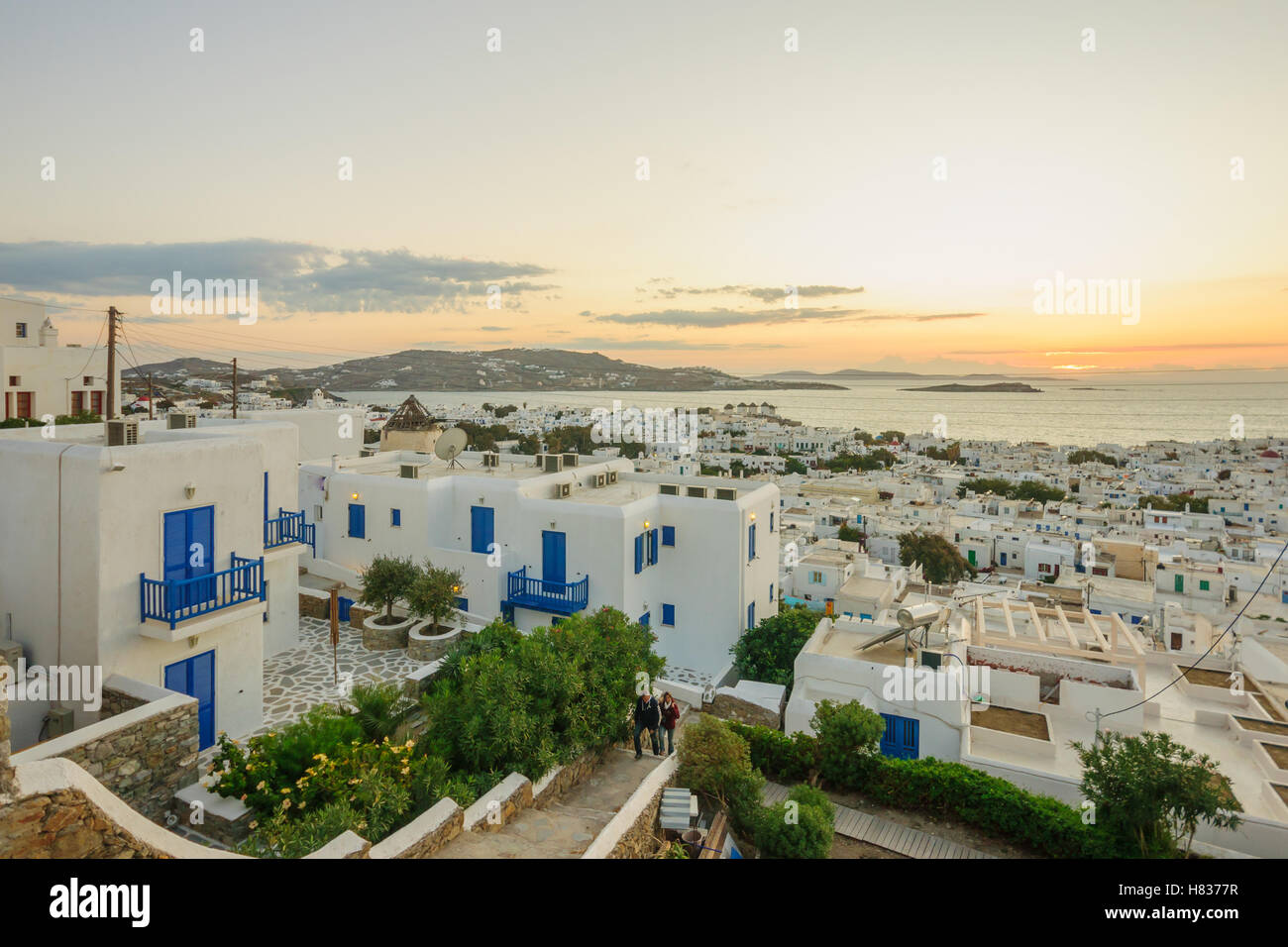 MYKONOS, GREECE - OCTOBER 02, 2011: Sunset scene of the Village, with local businesses, windmills, locals and visitors, in Mykon Stock Photo