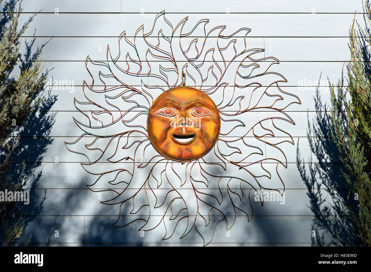 Copper sun face sculpture on building wall Stock Photo