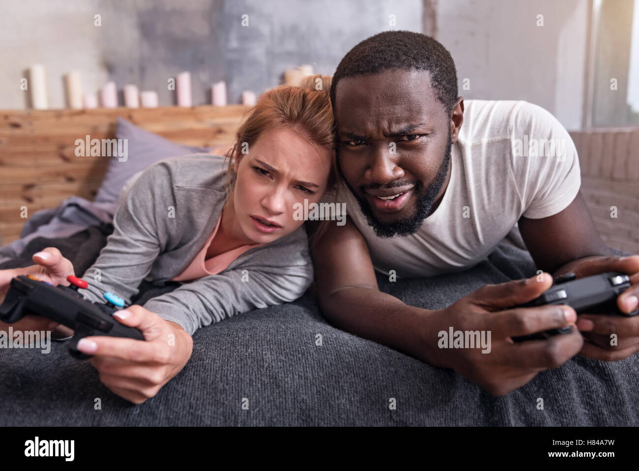 Amused couple playing video games in bedroom together Stock Photo