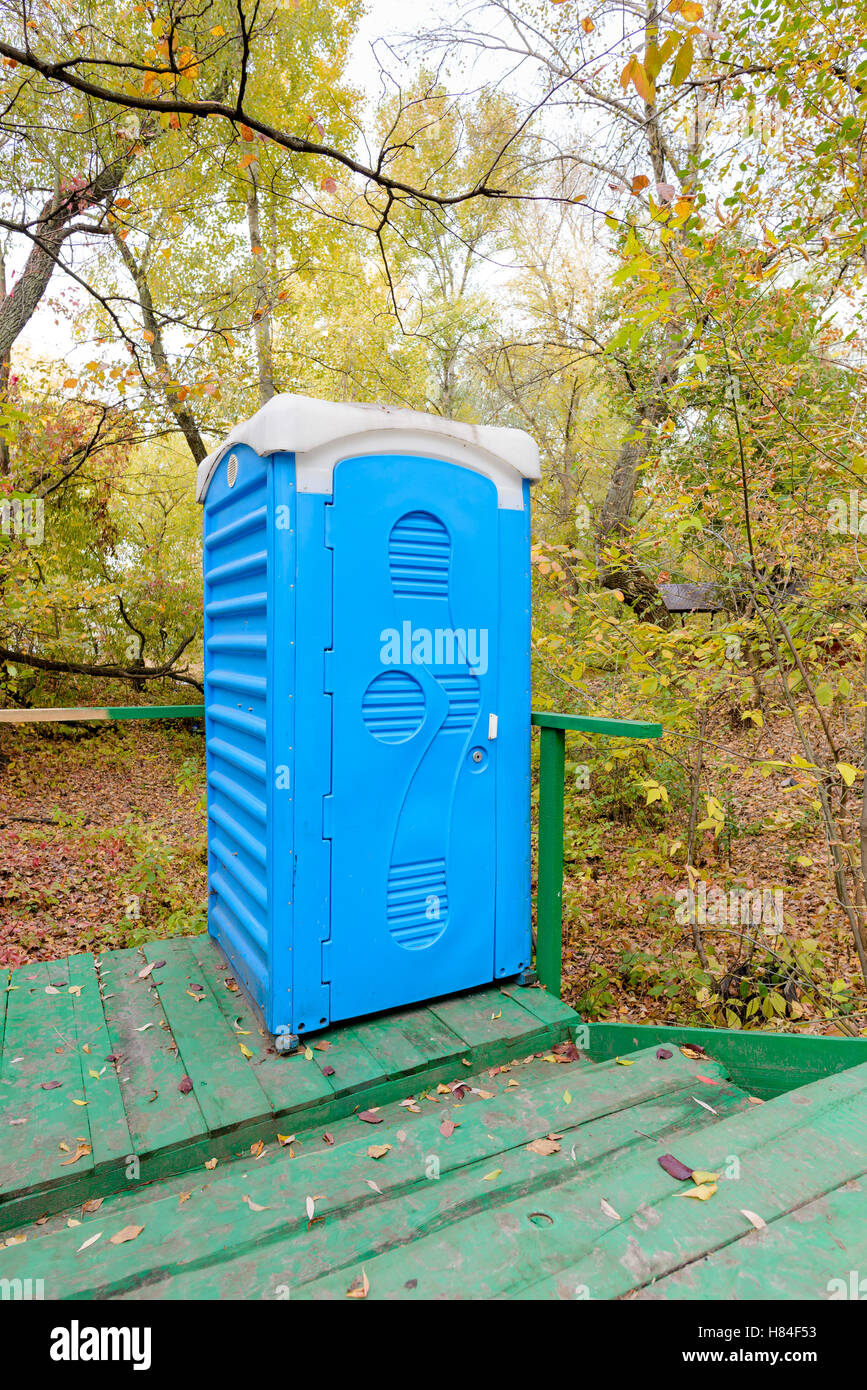 Blue outdoor chemical toilet in the woods in autumn Stock Photo