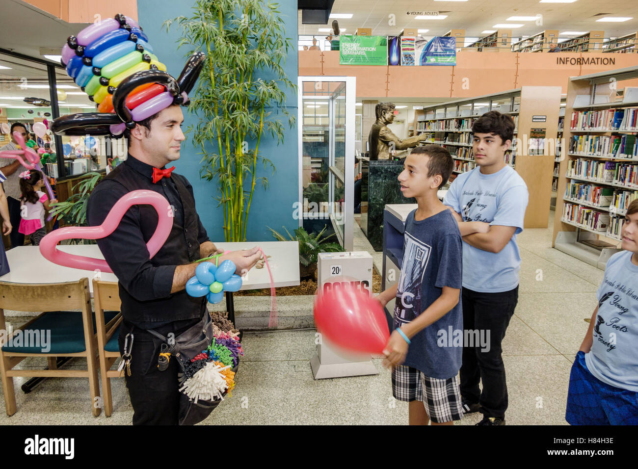 Miami Florida,Hialeah,JFK Library,Health & Literacy Fair,interior inside,Hispanic man men male,balloon artist,twister,modeling,hat,teen teens teenager Stock Photo