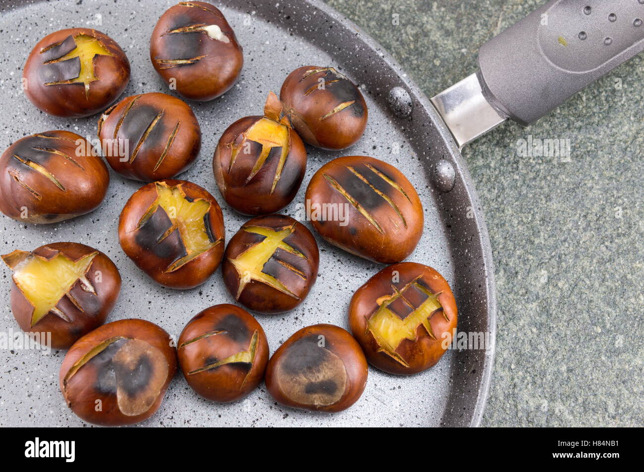 Roasted chestnuts on a stone cooking pan Stock Photo