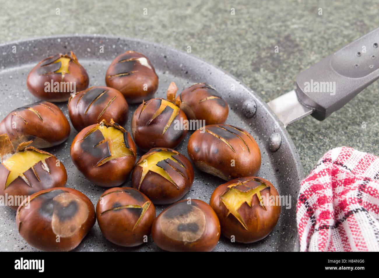 Roasted chestnuts on a stone cooking pan Stock Photo