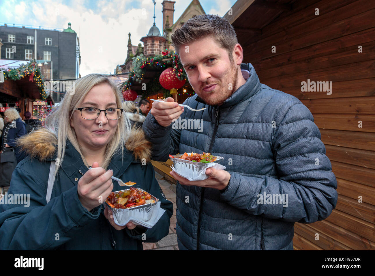 Glasgow, Scotland, UK. 10th November, 2016. Glasgow's annual and popular Christmas International food and gifts market opened today in St Enoch Square in the city centre with many stalls providing an extensive range of gifts and foreign foods. PAUL McGUIRE, from RENFREW and ROBYN HENDRY from Glasgow are enjoying some Asian styled food during their lunch break Credit:  Findlay/Alamy Live News Stock Photo