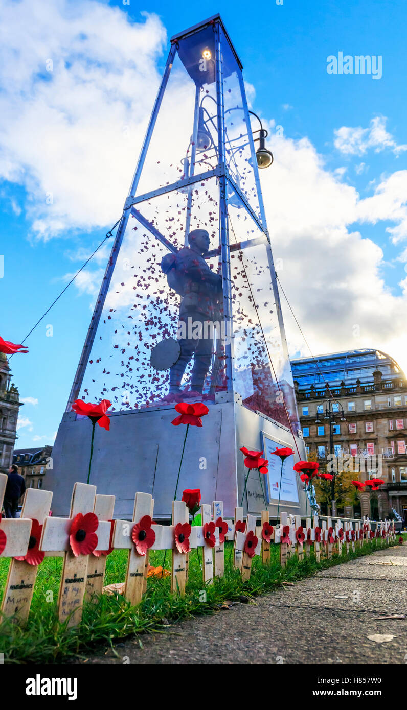 Glasgow, Scotland, UK. 10th November, 2016. In preparation for the Remembrance Services on 11 November the statue of 'Every Man Remembered' by MARK HUMPHREY, a 23 foot high brass statue of the Unknown Soldier enclosed in glass and with 100's of poppies floating in the case, is adorned by Remembrance Crosses and Solitary Poppies by members of the public and Poppy Scotland. The statue can be seen at the Remembrance Garden, George Square, Glasgow city centre. Credit:  Findlay/Alamy Live News Stock Photo
