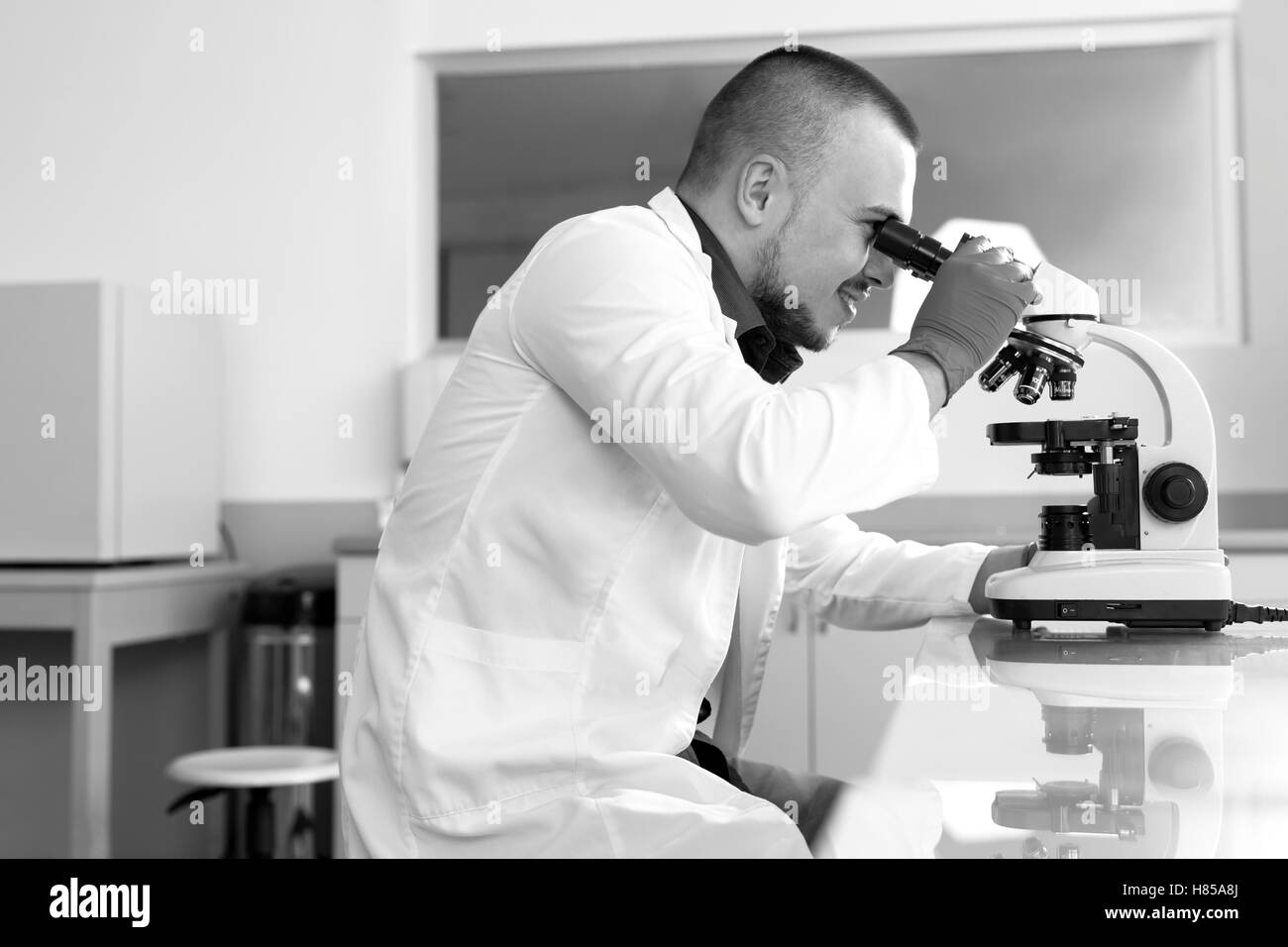 Young scientist investigating microbiological substance in microscope Stock Photo
