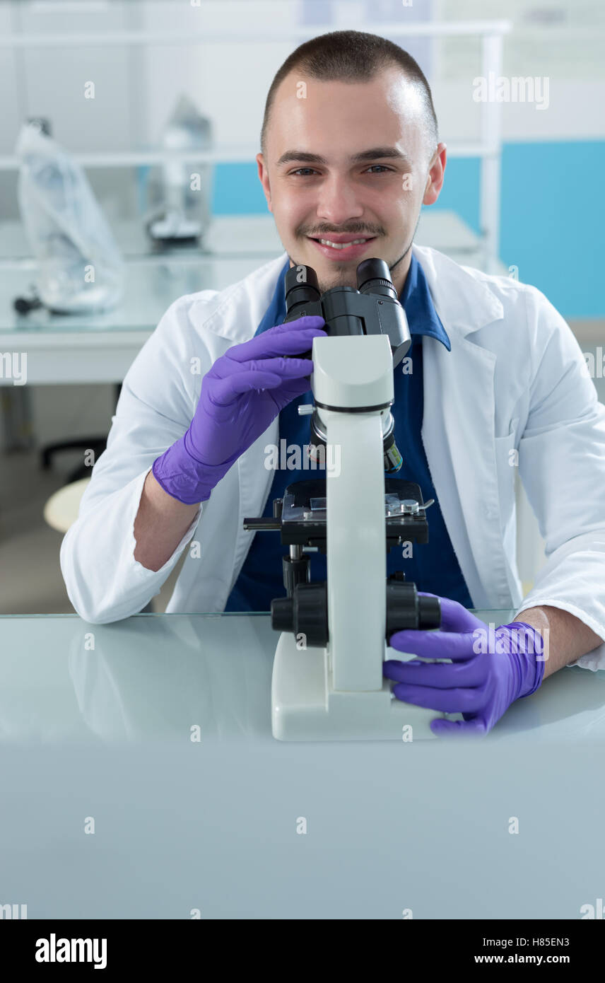 Young scientist investigating microbiological substance in microscope