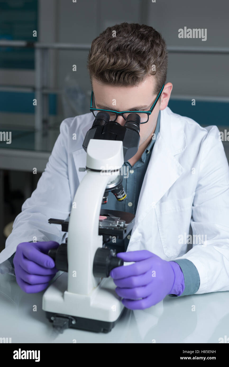 Scientist looking through a microscope in a laboratory Stock Photo - Alamy