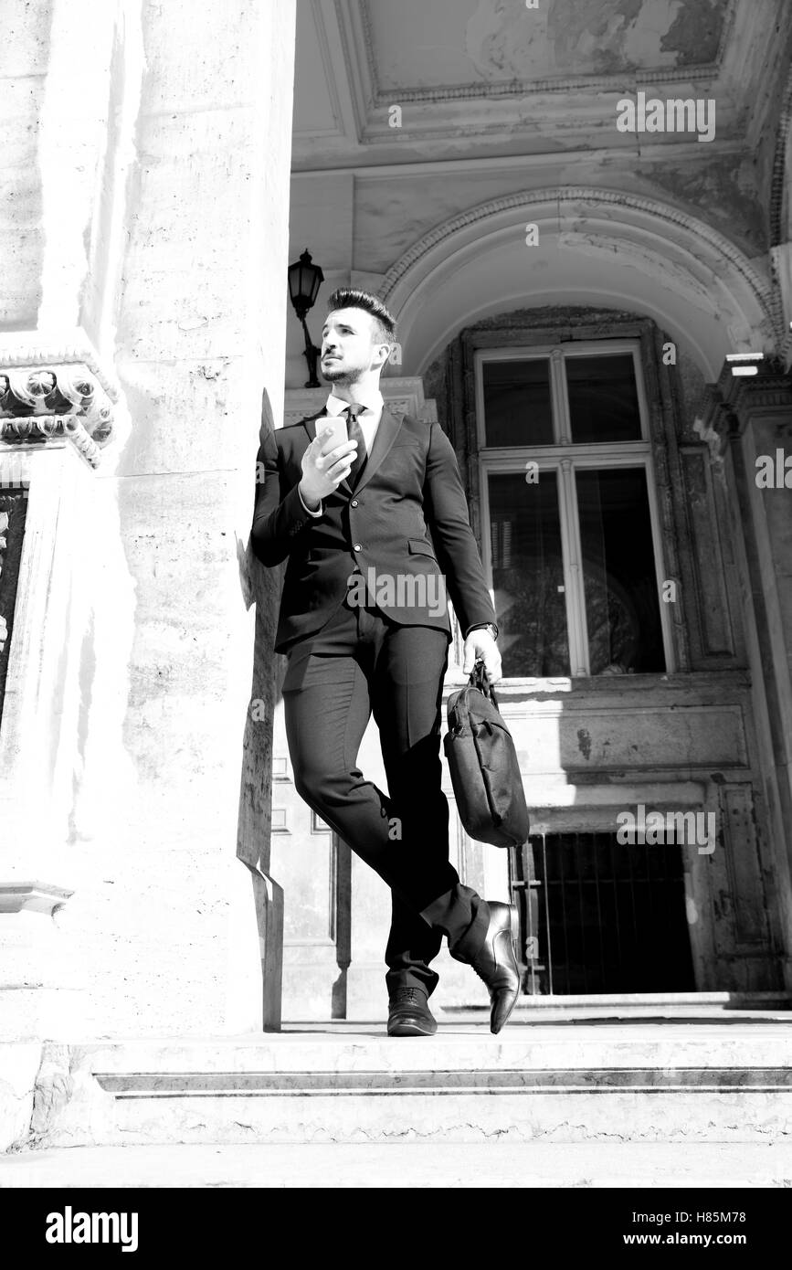 Young businessman waiting outside on the street, using his smartphone Stock Photo