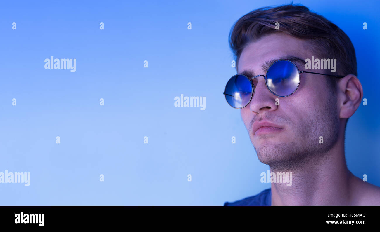 portrait of young man over blue background wearing sunglasses Stock ...