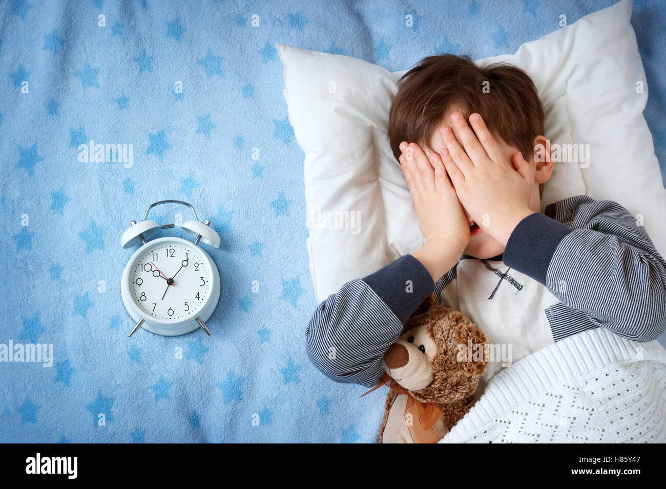 six years old child sleeping in bed with alarm clock Stock Photo