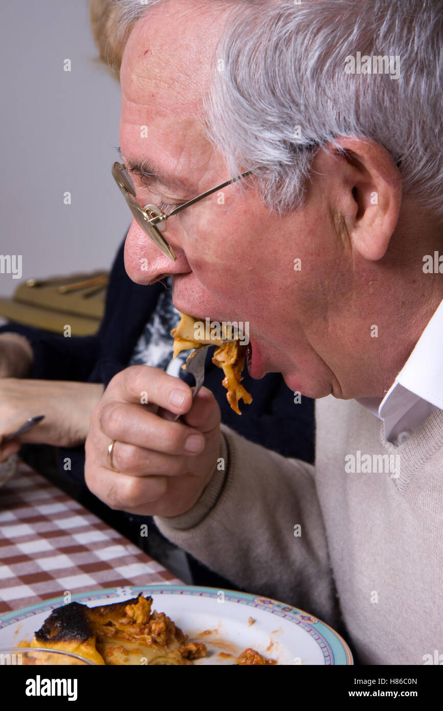 elderly man at table eating and relaxing Stock Photo