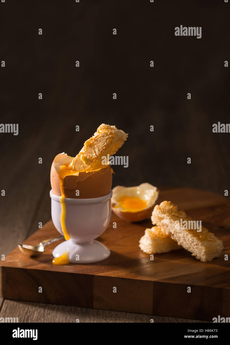 Toast dipped into a soft boiled egg creatively lit Stock Photo Alamy