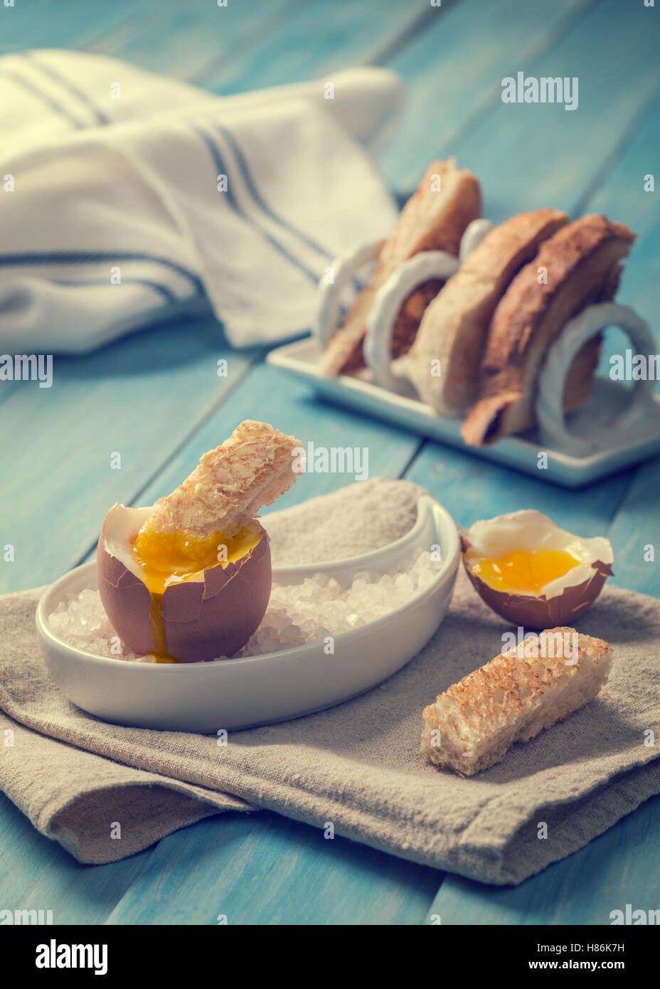 Buttered toast being dipped into soft boiled egg focus on dipped
