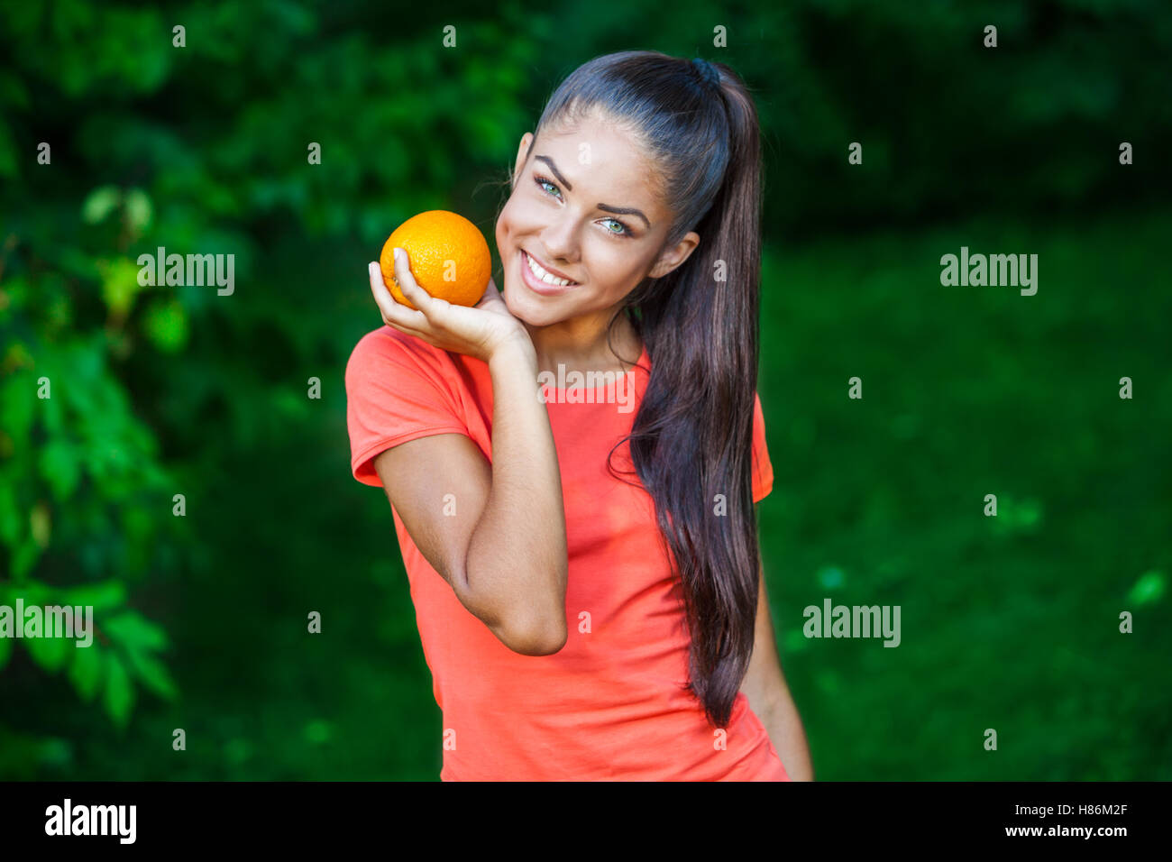 young beautiful brunette woman holding orange Stock Photo - Alamy