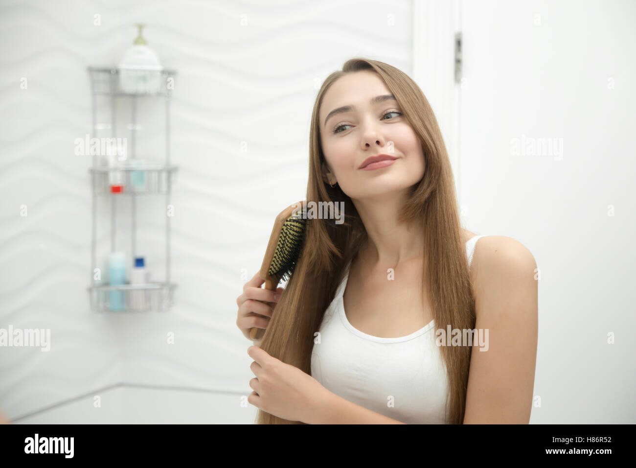 Portrait of a young smiling girl brushing her hair Stock Photo