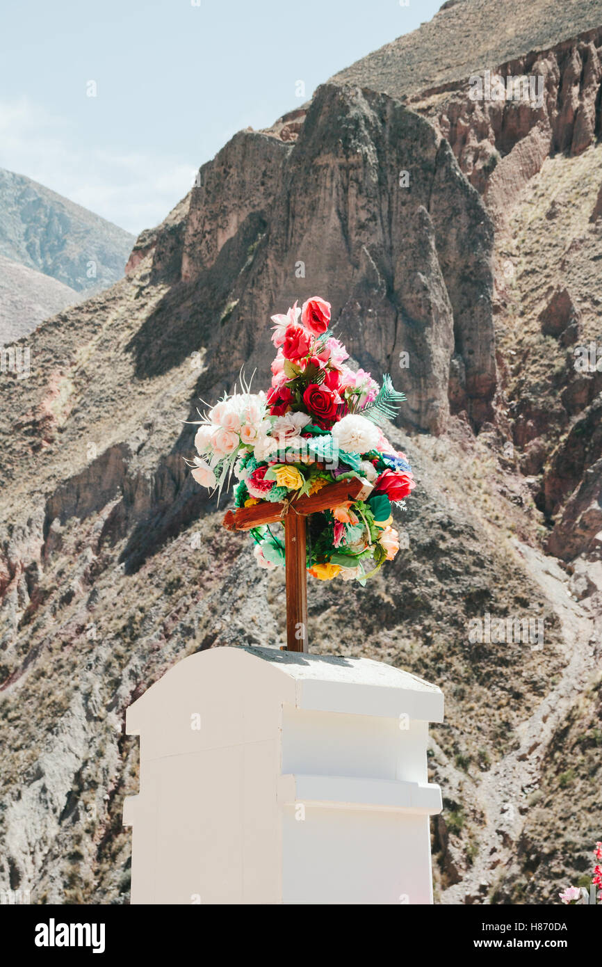 Catholic graveyard with mountains in the background. Tombstone with bright flowers on top. Stock Photo