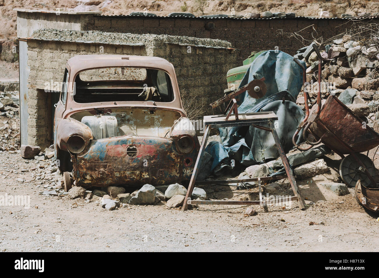 Broken and abandoned car amongst rubble and utensils in Iruya. Stock Photo
