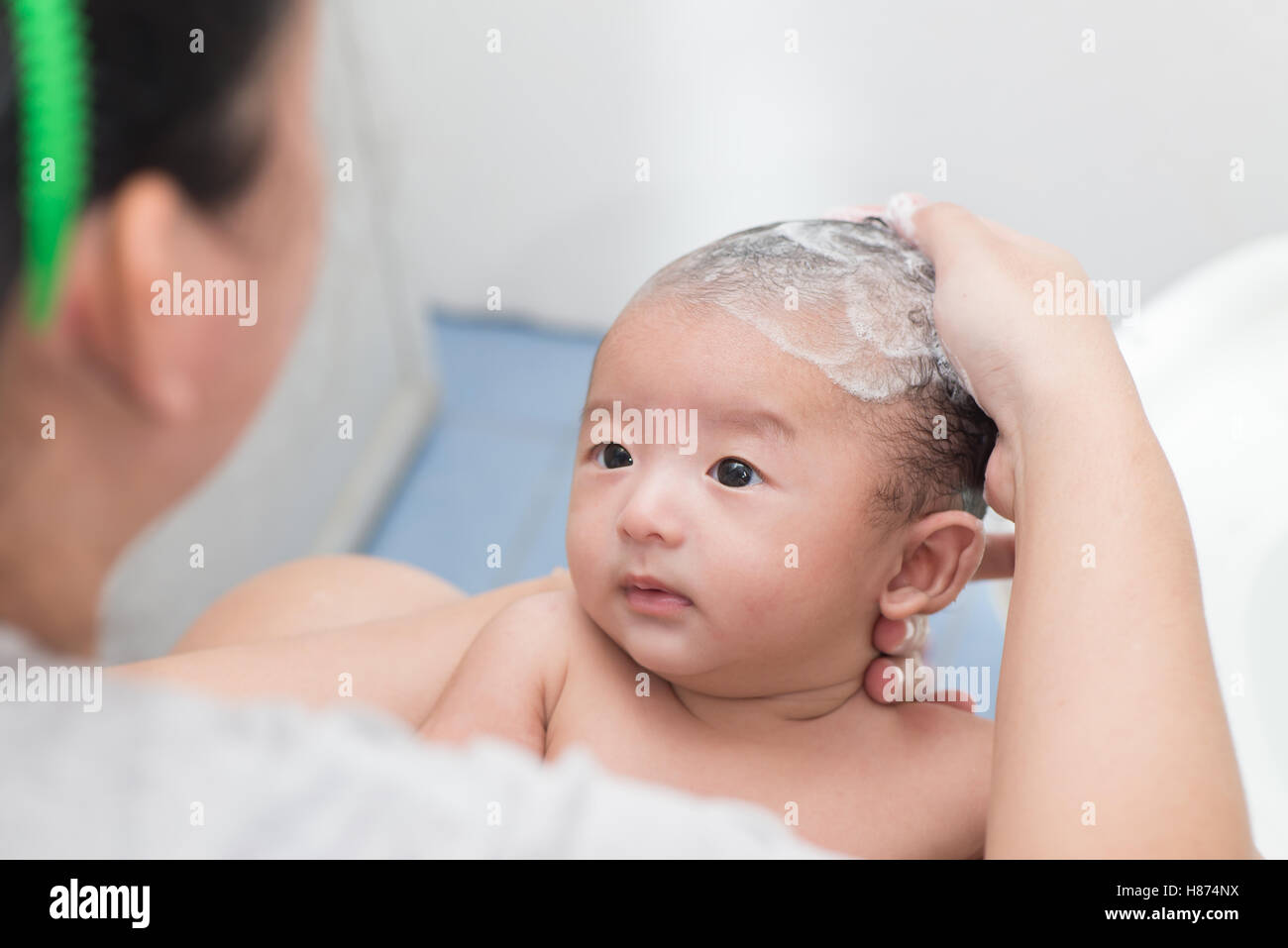 Mother give a bath her newborn baby in bathroom, focus at the eye Stock