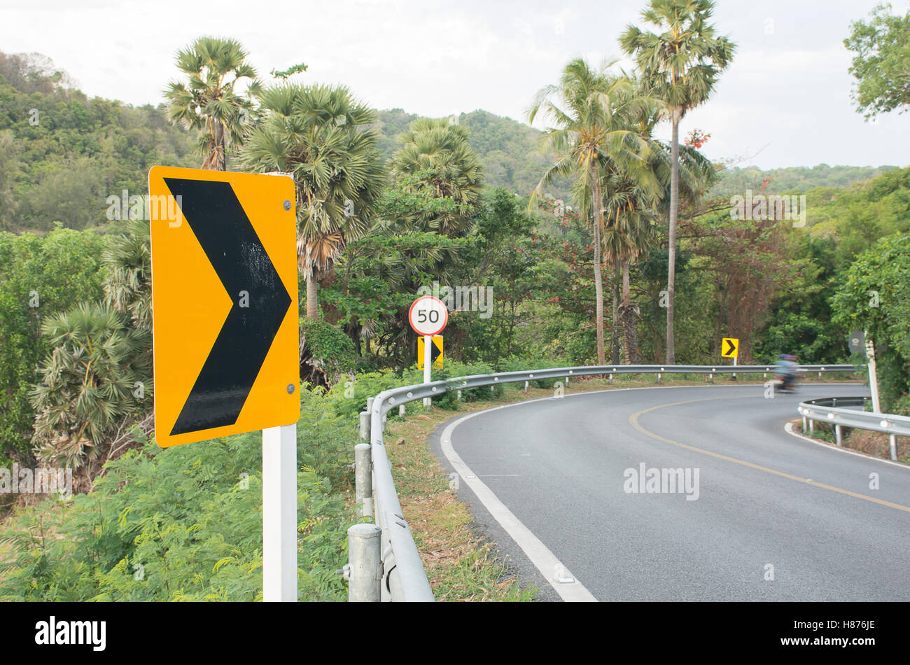 Curve road and right turning signal and Speed limit signs on the way down hill,AF Focused Stock Photo