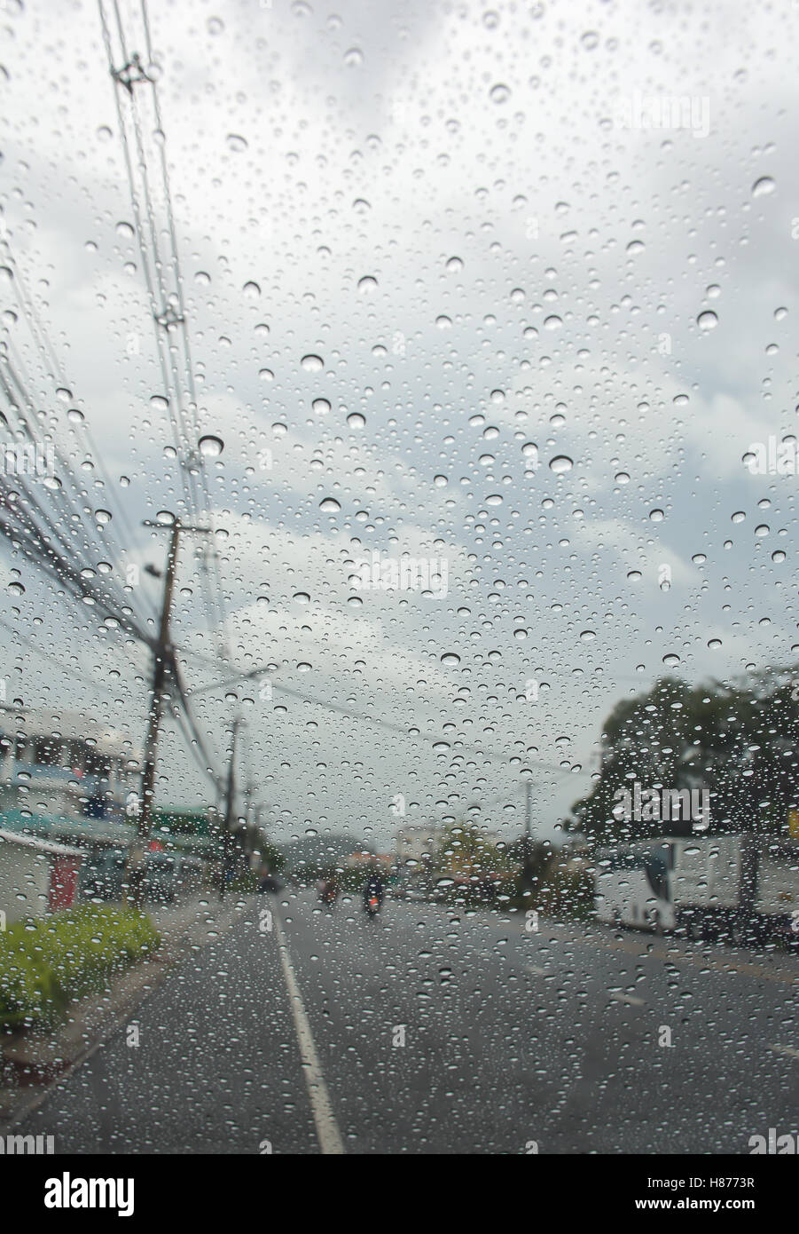 Rain drop on the car glass with road background, and clouds in the sky Stock Photo