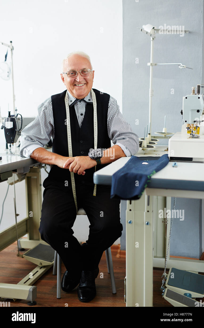 Smiling tailor sitting in workshop Stock Photo
