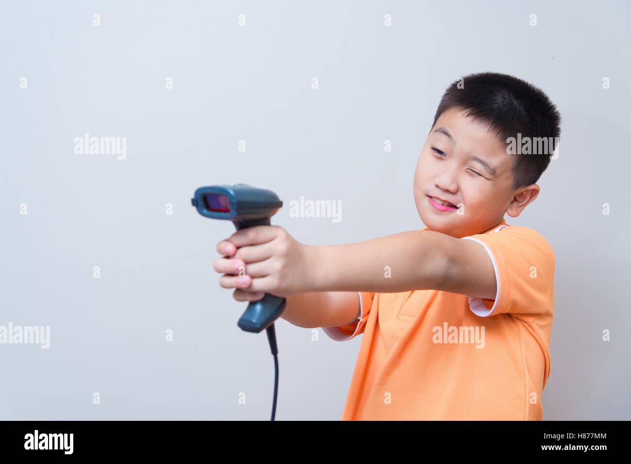 Asian boy aim a fake gun made with barcode scanner, studio shot, on ...
