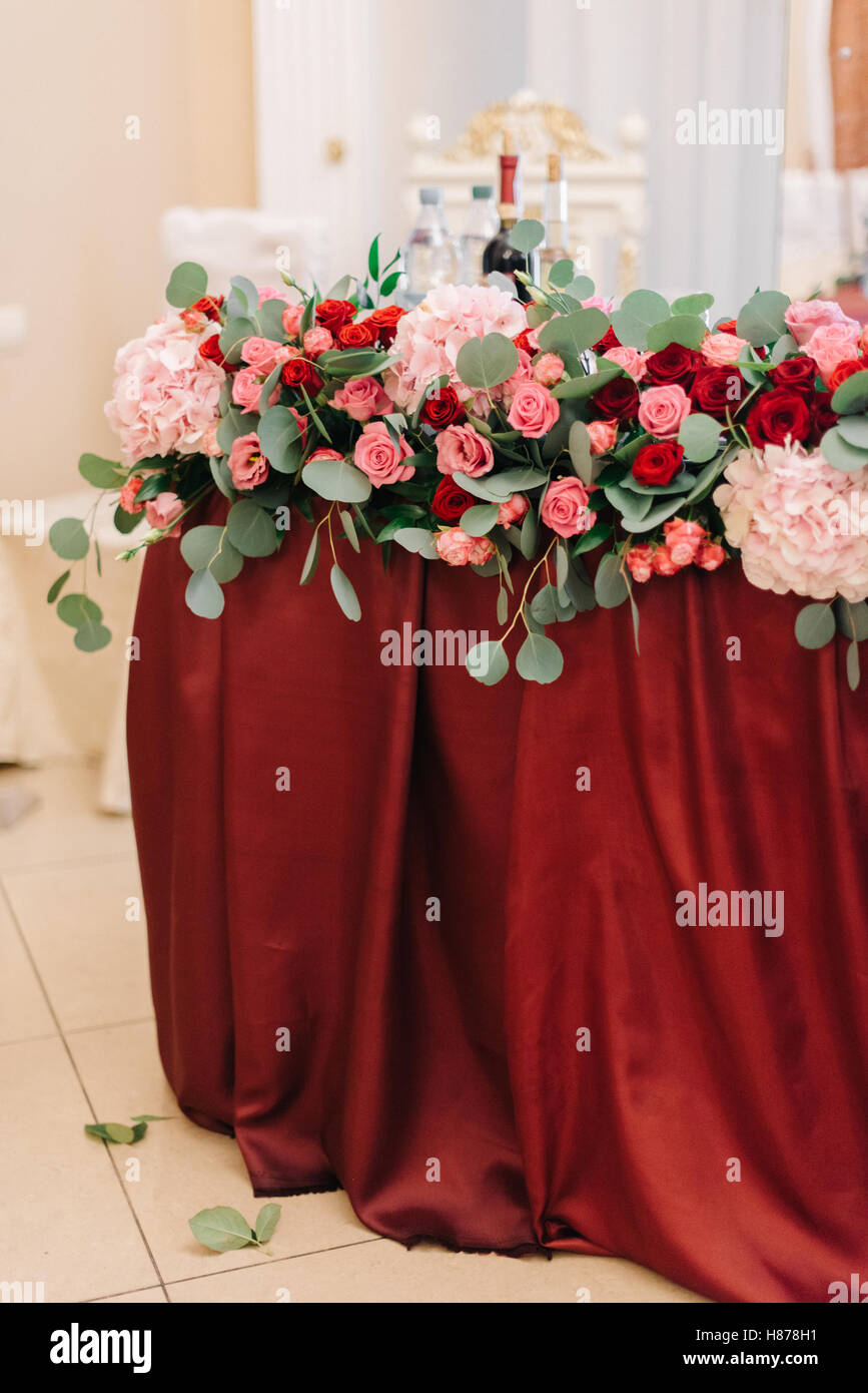 Festoons Table Flower festoon with greenery lies on red dinner table Stock Photo - Alamy