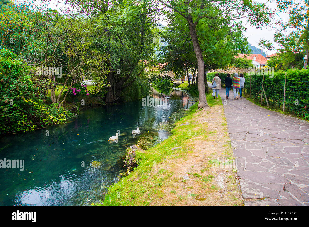 People walking along the river bank. River La Fuentona, Ruente, Cantabria, Spain. Stock Photo