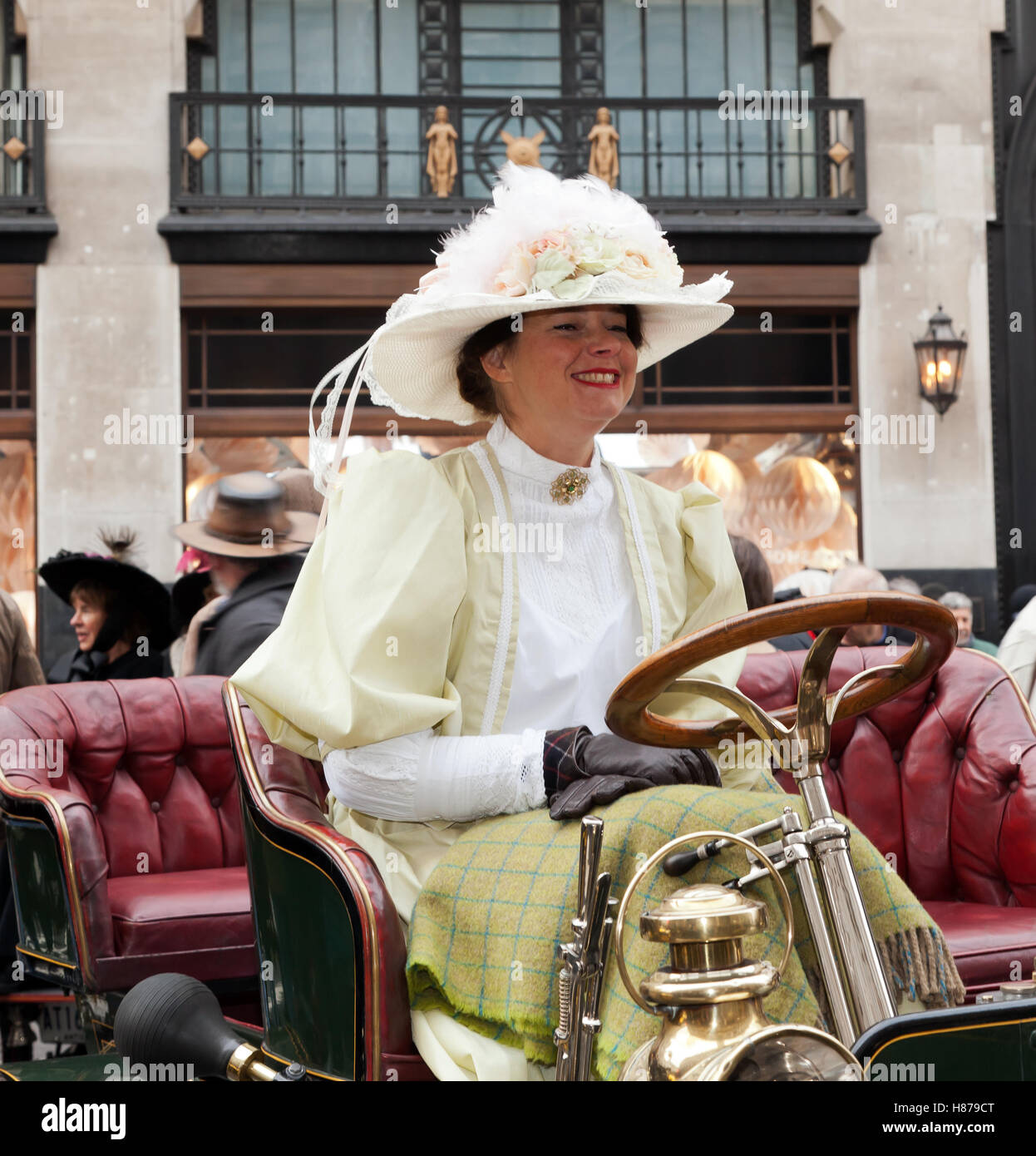 A smiling lady in period costume, sitting in a 1904 Norfolk veteran car, at the 2016 Regents Street Motor Show. Stock Photo