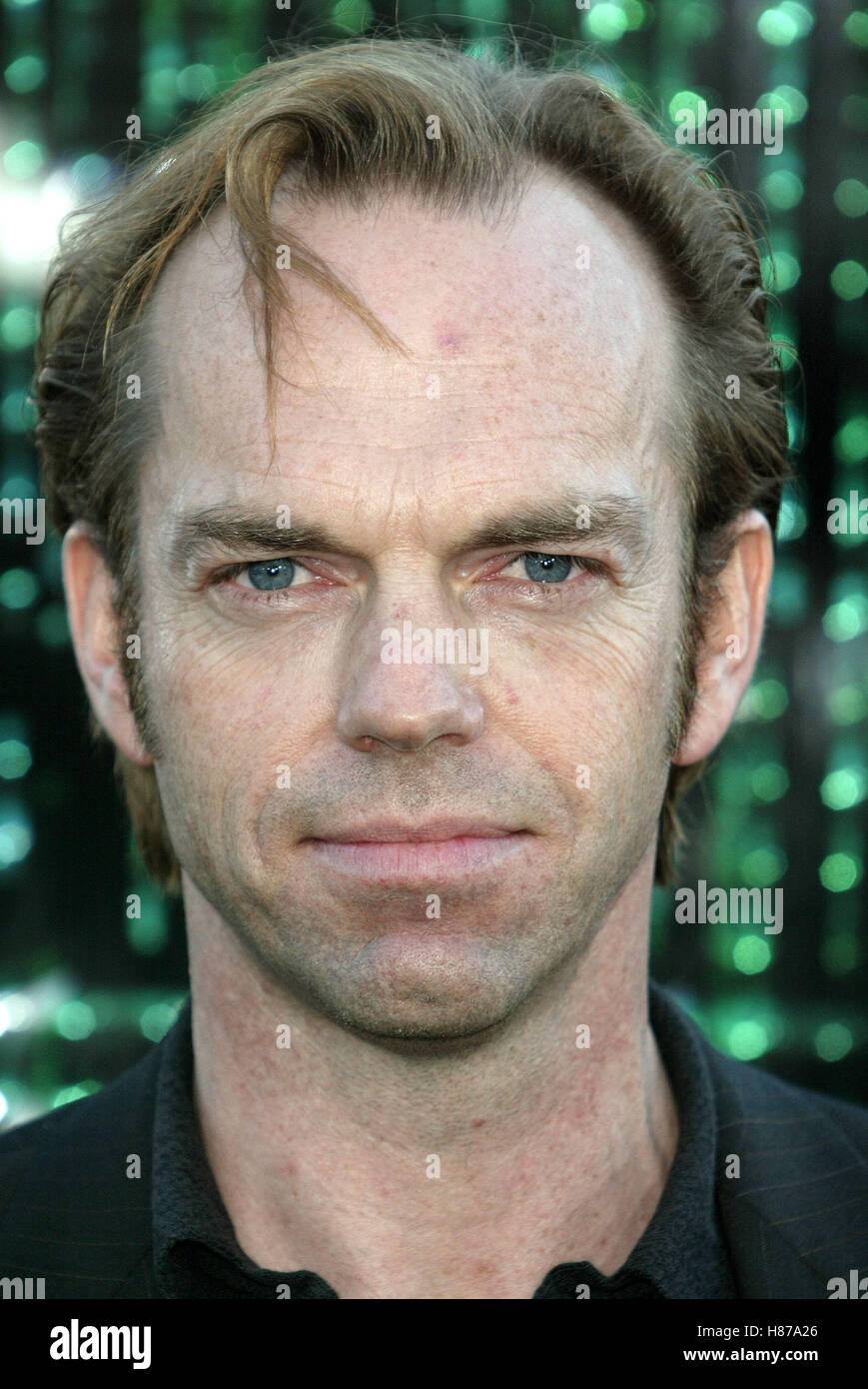 Young Hugo Weaving in a suit smoking a cigar with a