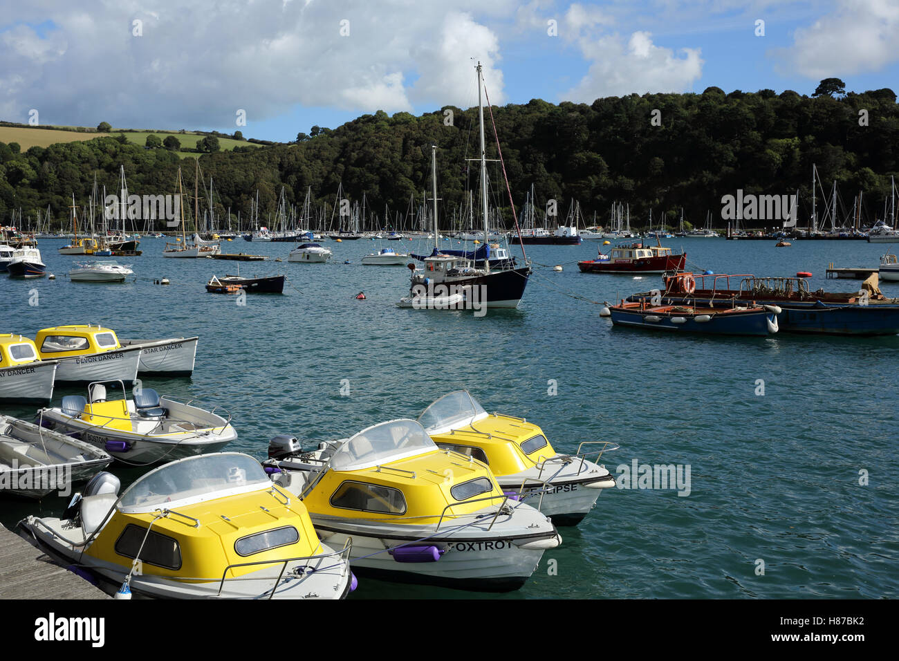 Motor boats for hire in Dartmouth, Devon, England, UK, with other boats and the river Dart in the background. Stock Photo