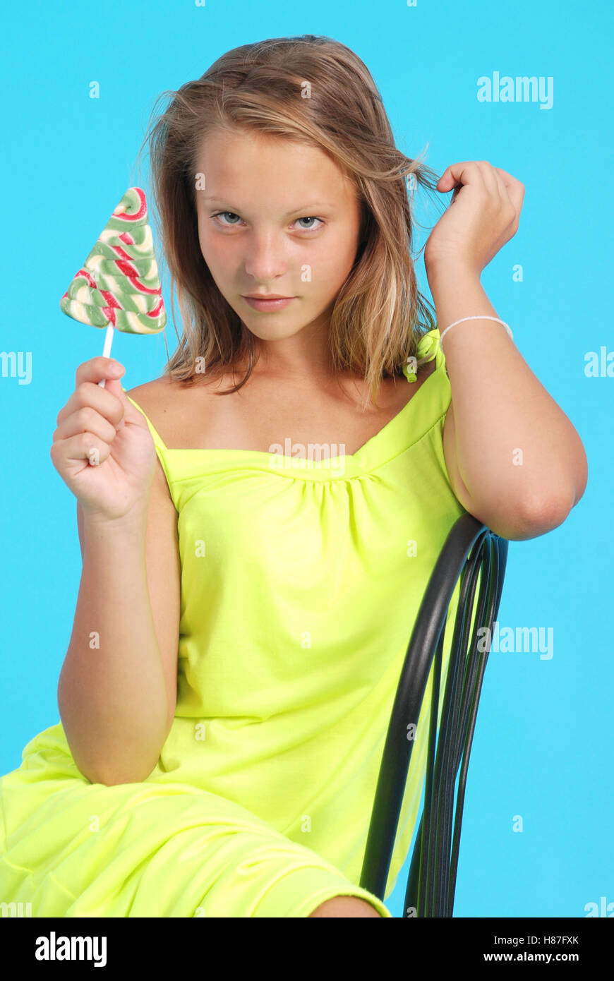Smiling girl sits on a chair isolated on blue Stock Photo - Alamy