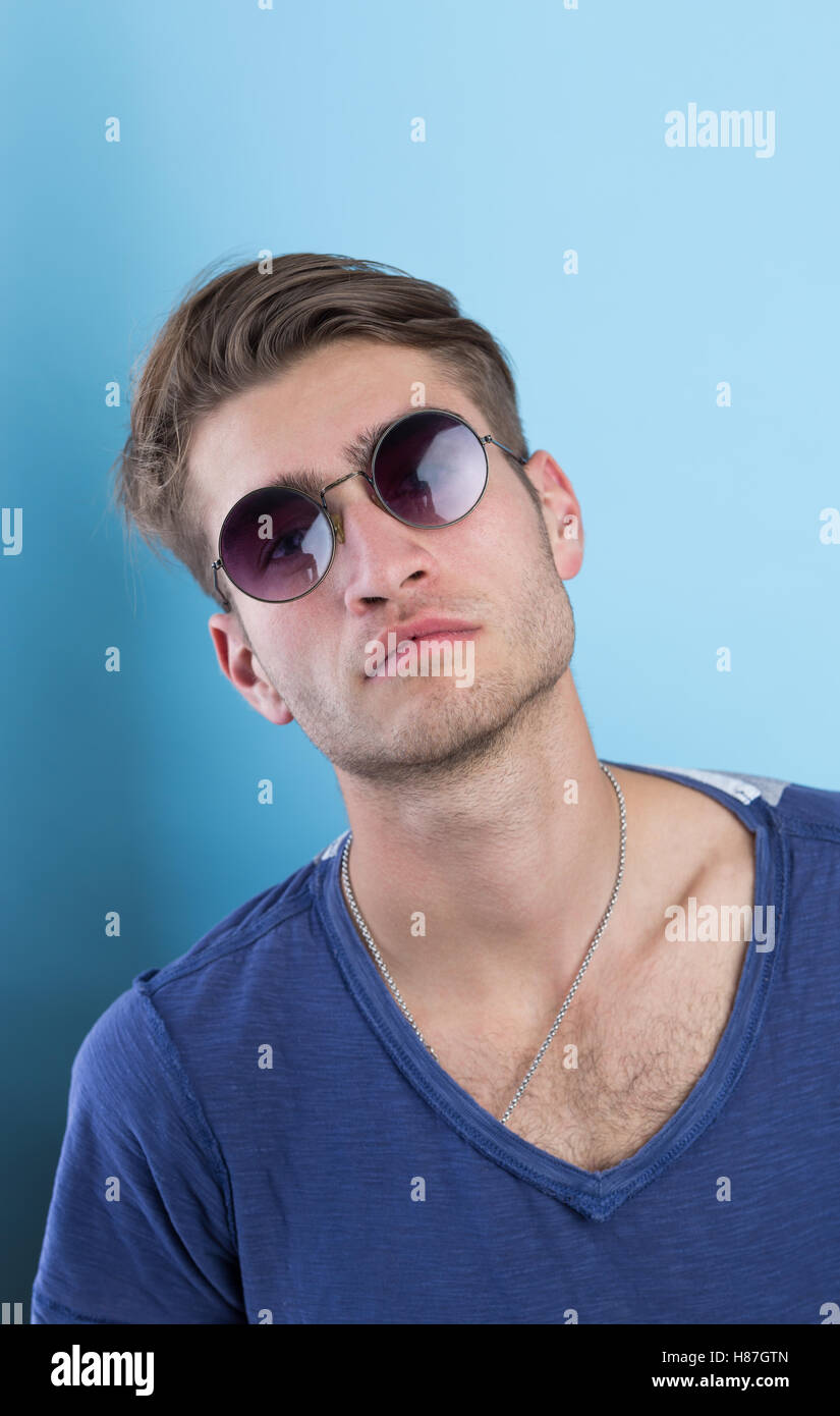 portrait of young man over blue background wearing sunglasses Stock ...