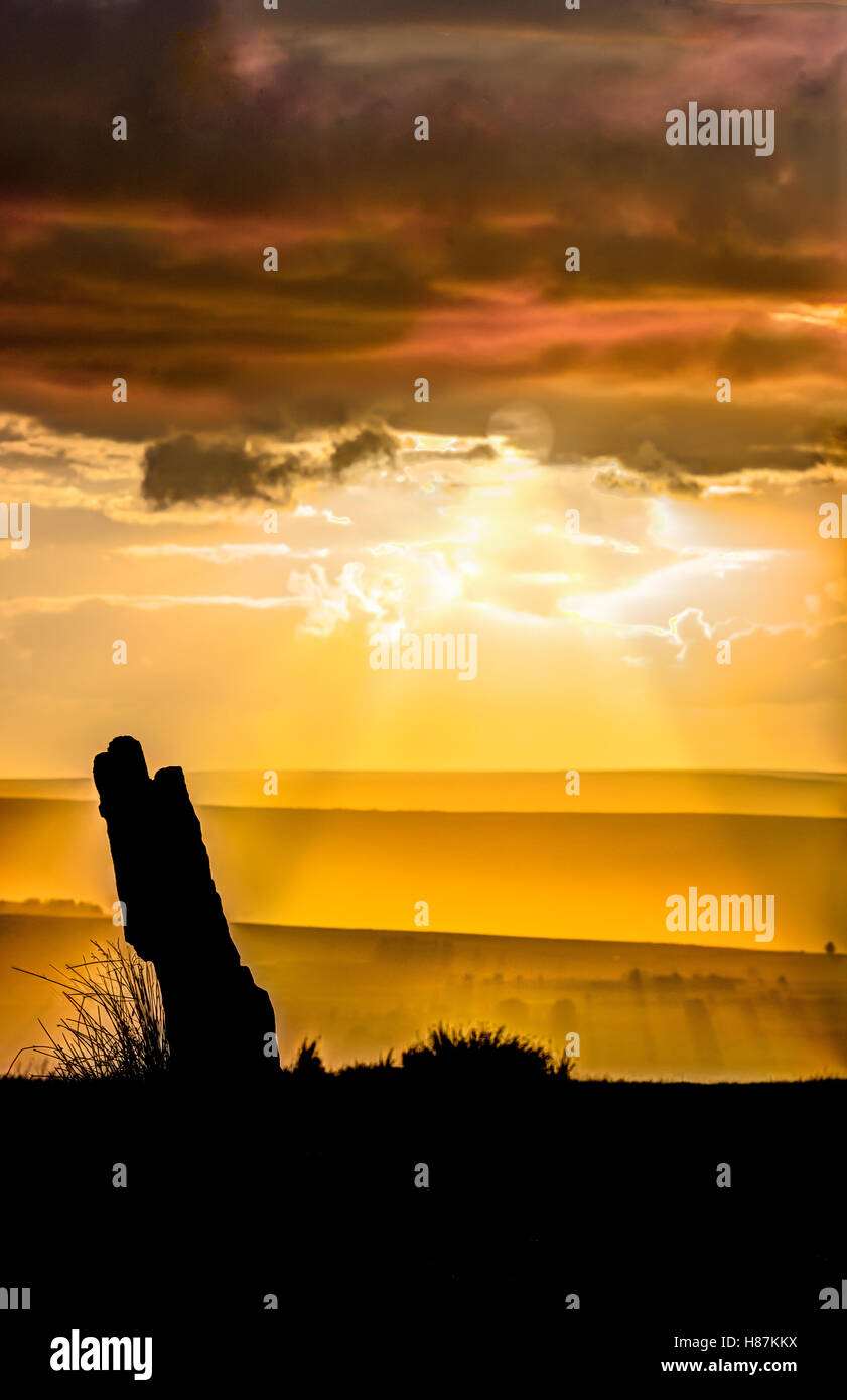 Sunset with a standing stone, North York Moors, UK. The standing stone is one of a group called High Bridestones. Stock Photo