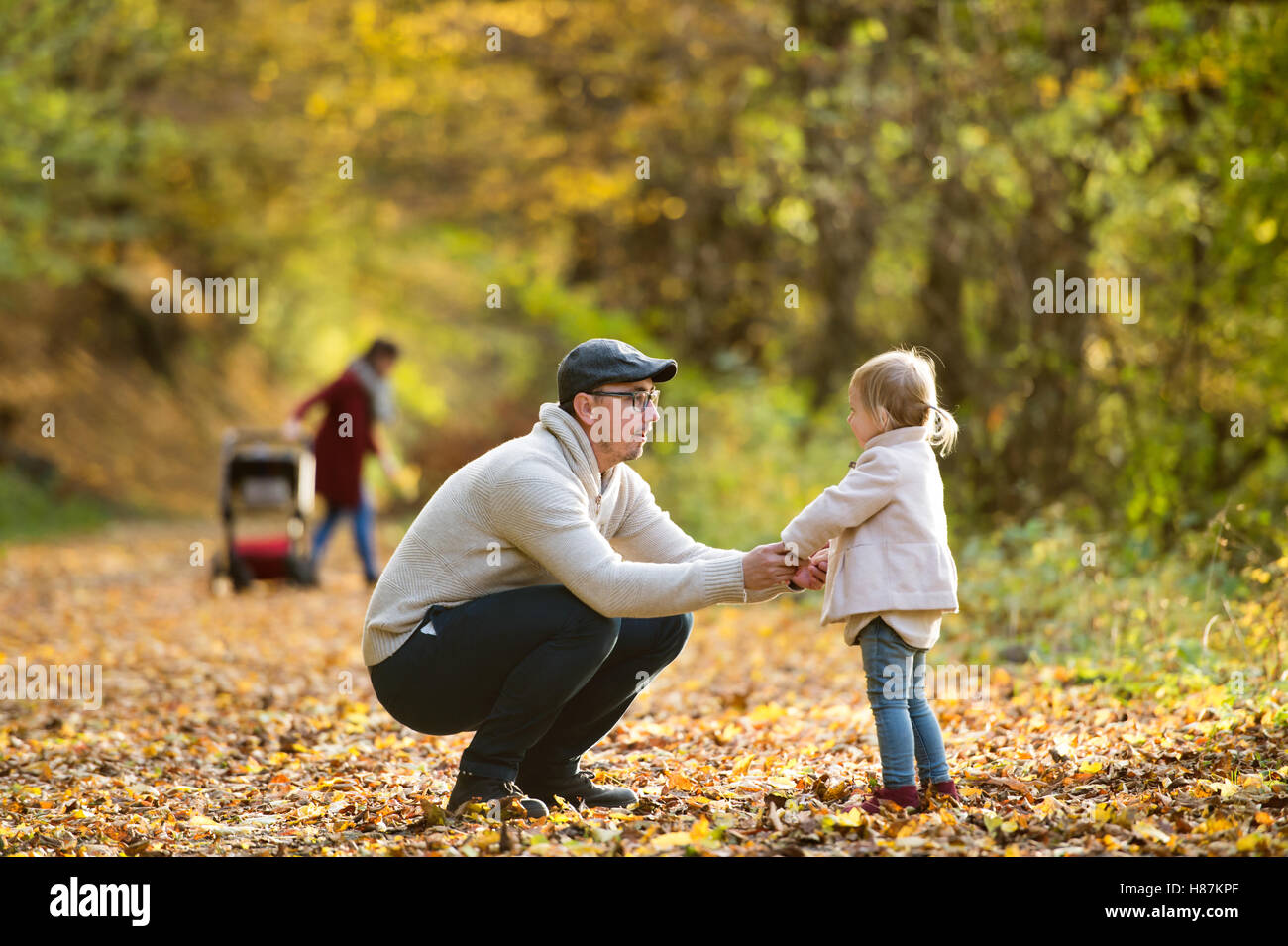 Beautiful young family on a walk in autumn forest Stock Photo - Alamy