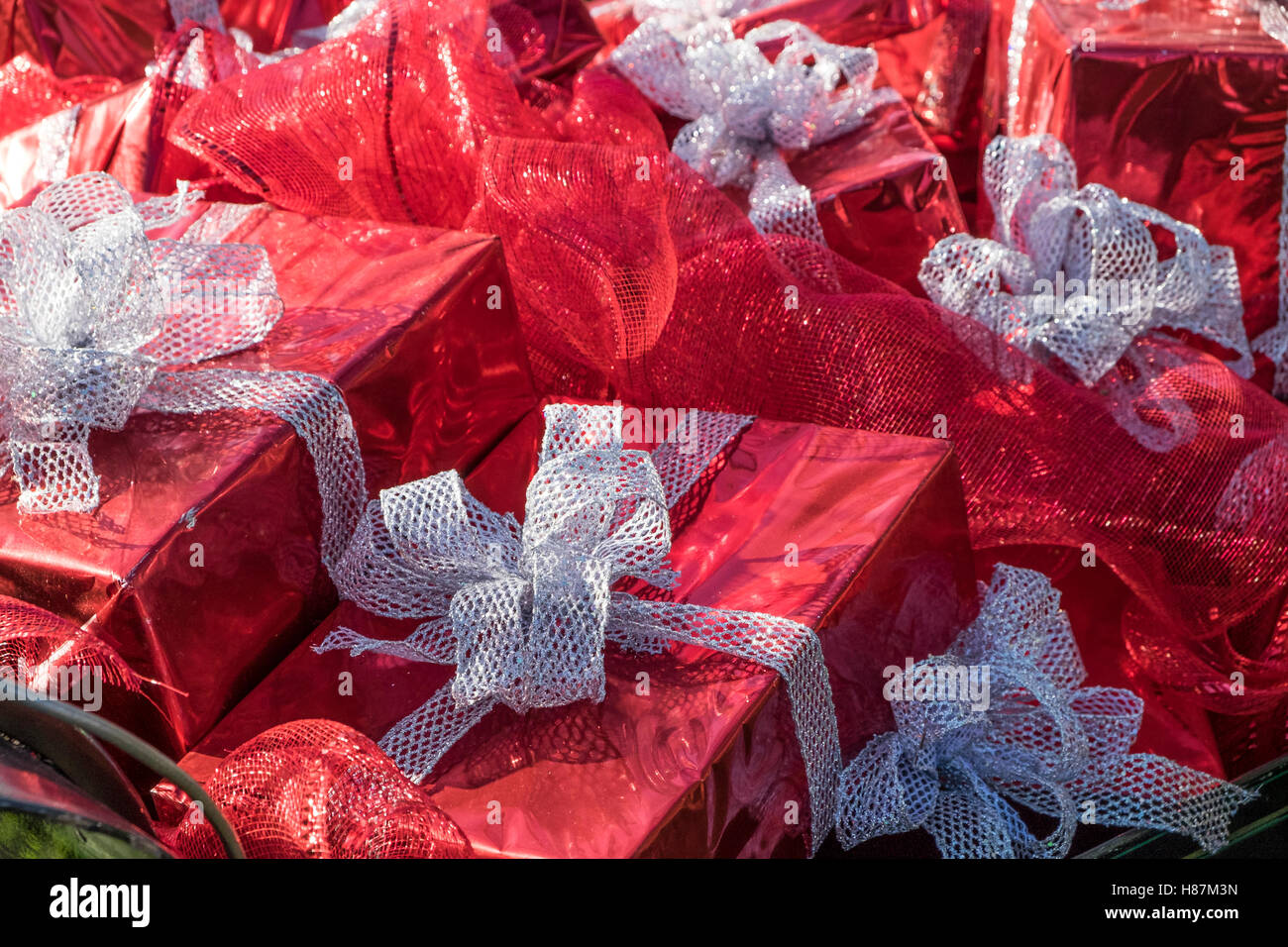Gifts wrapped in red foil paper and silver ribbon tied in bows. Stock Photo