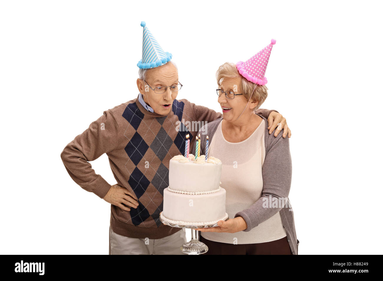 Elderly woman holding a birthday cake with candles and an elderly man ...