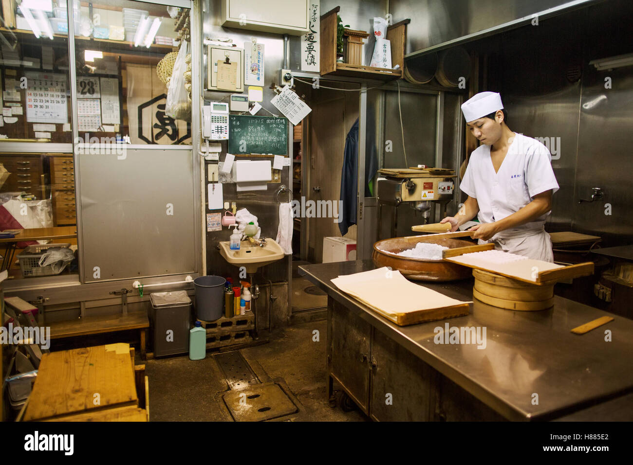A small artisan producer of wagashi. A man mixing a large bowl of ingredients and pressing the