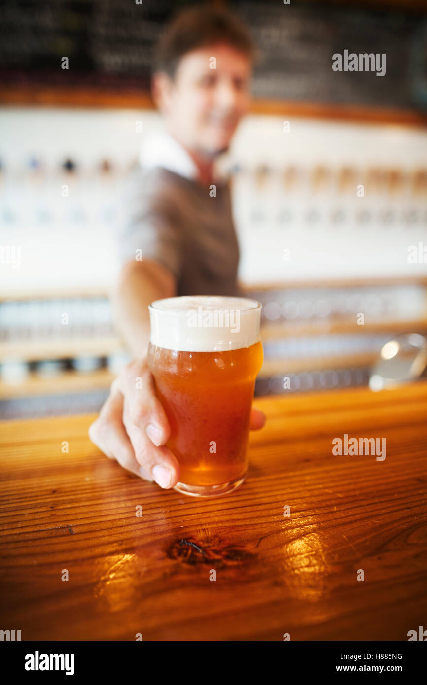 Beer glass standing on a counter, man in the background. Stock Photo